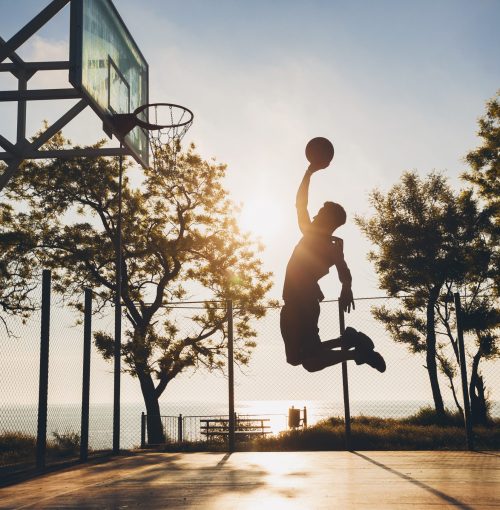 black man doing sports, playing basketball on sunrise, jumping silhouette